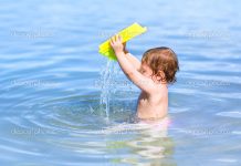 Bebé a brincar com a água na praia