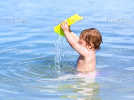 Bebé a brincar com a água na praia
